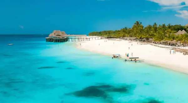 Playa paradisíaca en Tanzania en agosto. Aguas turquesas, arena blanca, palmeras y un muelle con un restaurante.
