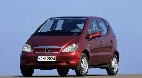 Czerwony Mercedes A Klasa 2001 z tablicą rejestracyjną S MN 2824, zaparkowany na tle błękitnego nieba.