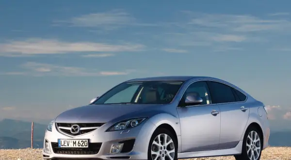 Srebrna Mazda 6 na tle błękitnego nieba. Wiele osób szuka mazda 6 opinie przed zakupem.