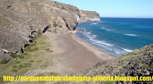 Playa virgen de cala principe, Cabo de Gata, con acantilados rocosos y mar azul.