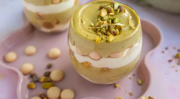 Pyszny deser z warstwami kremu pistacjowego z mascarpone, ciasteczek i posypką z orzechów pistacjowych.