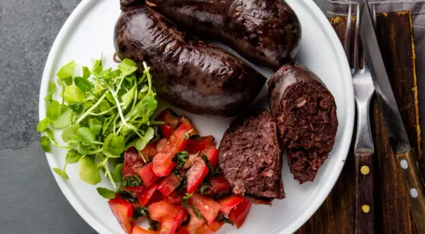 Kaszanka na talerzu z pomidorami i rukolą. Zastanawiasz się nad kaszanka kcal? To sycące danie.