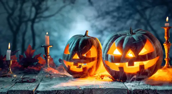 Gruselige Kürbisse mit Kerzenlicht und Herbstlaub. Ein Hauch von Mysterium, das an den Halloween Ursprung in Deutschland erinnert.