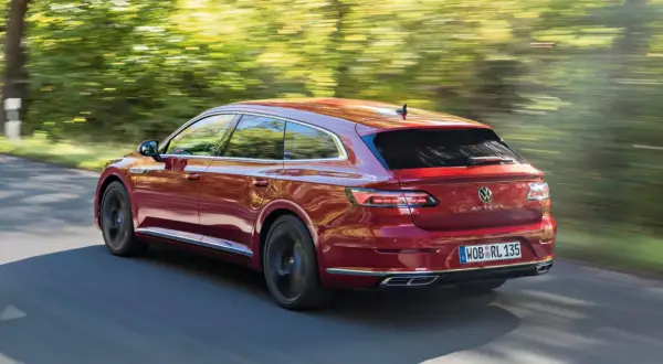 Czerwony Volkswagen Arteon Shooting Brake w ruchu na tle rozmytego krajobrazu.