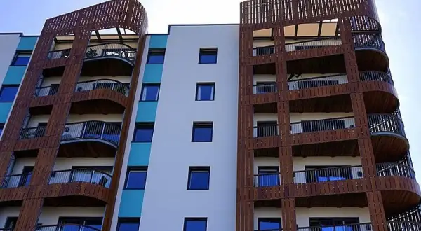 Moderne Wohnanlage mit vielen Balkonen, die von Holzlamellen umrahmt sind. 250 Baugb.