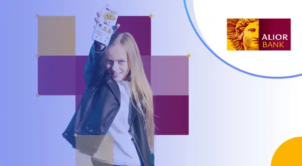 Uśmiechnięta dziewczyna prezentuje telefon z aplikacją Alior Bank. To idealne konto dla dziecka, które uczy się finansów.