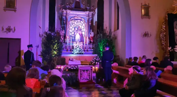 Wnętrze bazyliki Grobu Pańskiego, przygotowania do nocnej modlitwy. Wierni siedzą w ławkach, przy ołtarzu stoi wartownik.