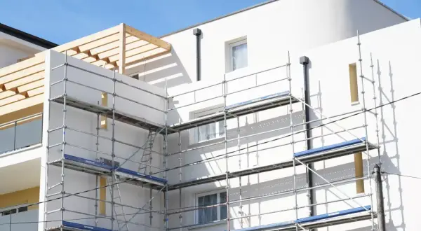 Immeuble blanc en construction avec échafaudages. Idéal pour un modèle lettre bailleur sociaux pour travaux.