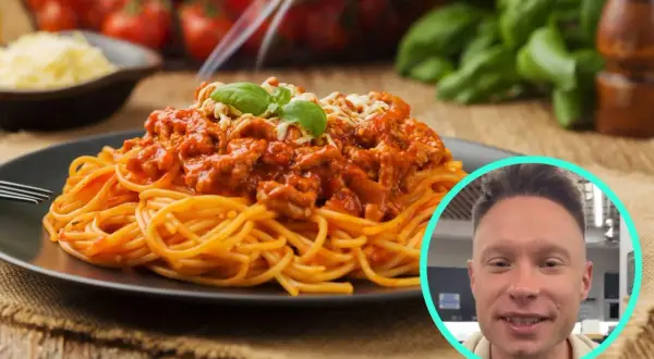 Pyszne spaghetti bolognese na talerzu, a obok uśmiechnięty mężczyzna. Zastanawiasz się, ile kcal ma spaghetti bolognese?