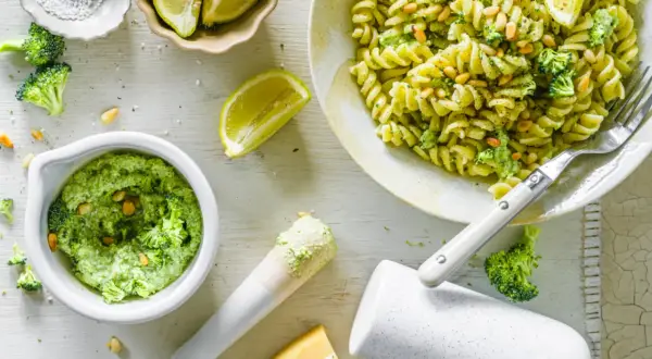 Frische Pasta mit cremigem Brokkoli Pesto, Pinienkernen und Zitrone. Zutaten für das Pesto sind sichtbar.