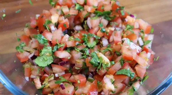 Świeża, kolorowa salsa z pomidorów, cebuli i kolendry w szklanej misce. Idealna do nachos lub jako dodatek do dań.