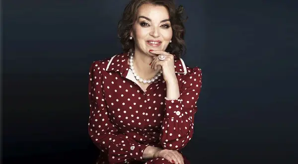Uśmiechnięta kobieta w sukience w białe kropki, niczym z lat 50. Jej styl to klasyczna polka.