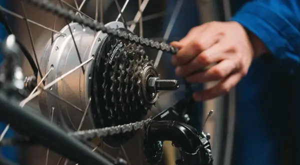 Ręka reguluje przerzutki w rowerze, poprawiając płynność jazdy. Widoczna kaseta Shimano i przerzutka.