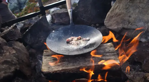Kolbulle smet fräser i stekpannan över öppen eld. En klassisk fjällmåltid tar form.