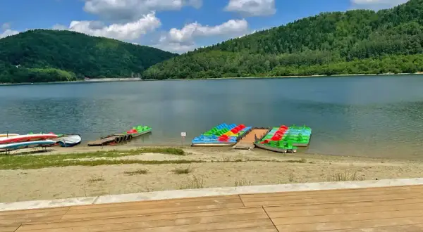 Kolorowe rowerki wodne i kajaki czekają nad spokojnym jeziorem w górach.