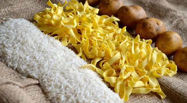 Reis, Nudeln und Kartoffeln liegen auf Jute. Was hat mehr Kalorien, Reis oder Kartoffeln? Die Antwort ist nicht so einfach.