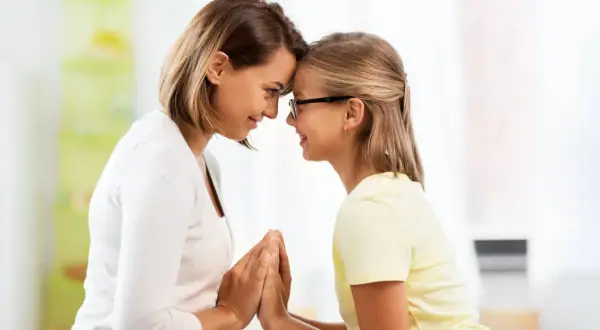 Madre e figlia si guardano con affetto, le fronti unite. Un momento di connessione profonda, che a volte può nascondere la psicologia di una madre invidiosa della figlia.