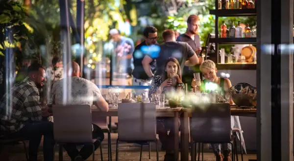Ludzie siedzą przy stole w restauracji Olivia Business Centre, pijąc i rozmawiając.