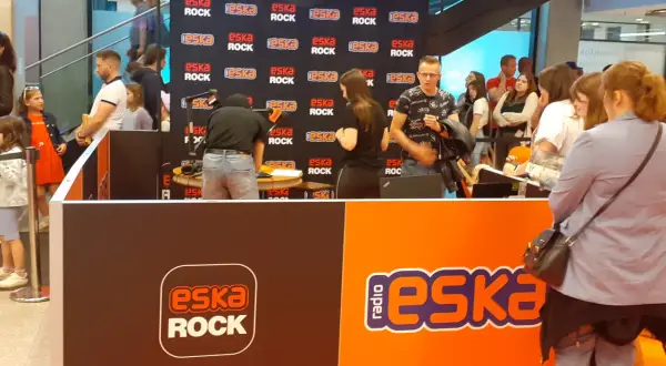 Stoisko radiowe Eska Rock z ludźmi i logo stacji.
