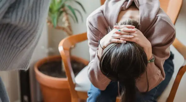 En person sitter med huvudet i händerna, kanske överväger effekterna av anafranil och alkohol.