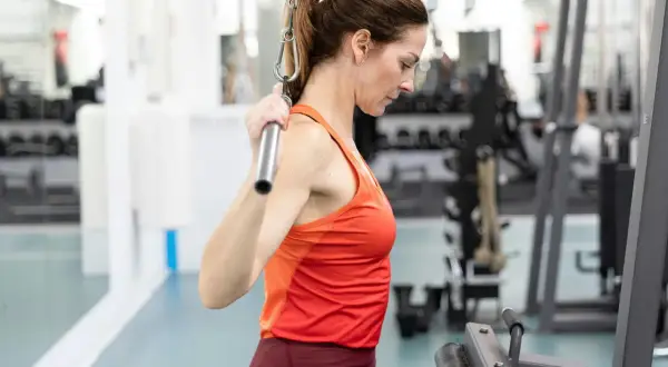 Kvinna utför lat pulldown i gymmet.