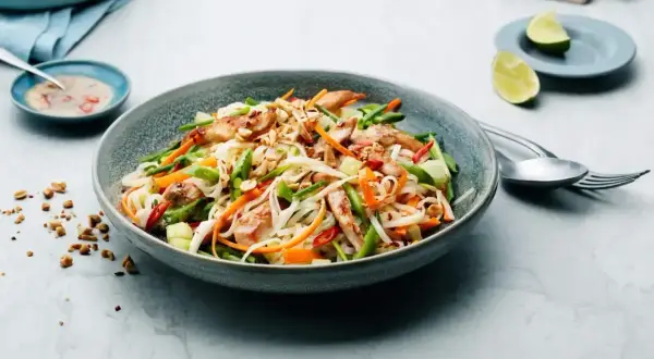 En läcker asiatisk sallad med nudlar, kyckling, grönsaker och jordnötter. Serveras med en krämig dressing och limeklyftor.