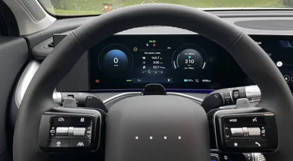 Wnętrze samochodu elektrycznego marki Hyundai. Na ekranie widoczny zasięg 310 km, zużycie energii i inne dane.