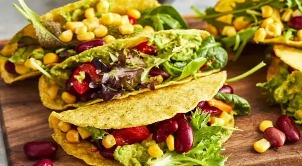 Knusprige, vegetarische Tacos gefüllt mit Guacamole, Kidneybohnen, Mais, Tomaten und Salat. Ein bunter Genuss!