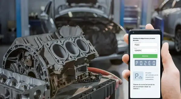 Mano sostiene móvil con código P02ED, buscando información sobre un motor Peugeot en taller mecánico.