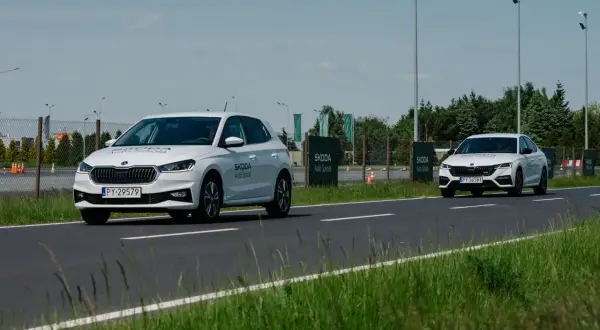 Białe Skody na torze szkoleniowym, jedna próbuje wyprzedzanie drugiej.