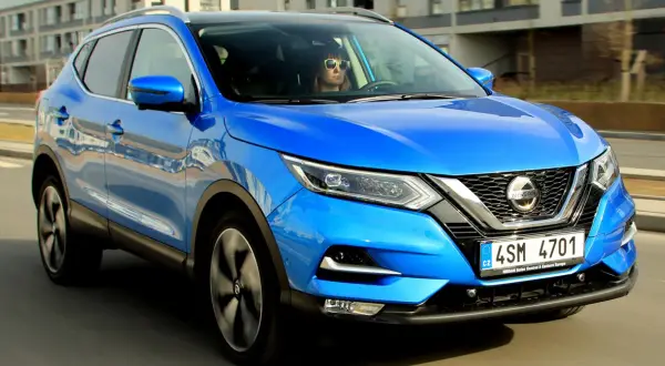 Niebieski Nissan Qashqai w ruchu. Kierowca w okularach przeciwsłonecznych. Sprawdź nissan qashqai wymiary.