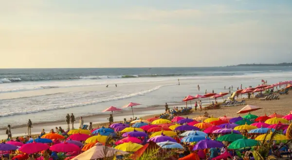 Kolorowa plaża na Bali, pełna parasoli i ludzi relaksujących się na leżakach. Idealne miejsce na wakacje.