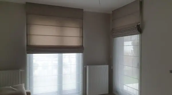 Eleganckie rolety rzymskie i zasłony tworzą przytulną atmosferę w pokoju.