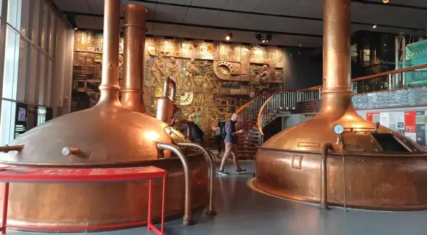 Interior del museo Estrella Galicia con grandes cubas de cobre y un mural histórico.