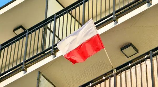 Polska flaga powiewa na balkonie. Biało-czerwone barwy symbolizują dumę i historię narodu.