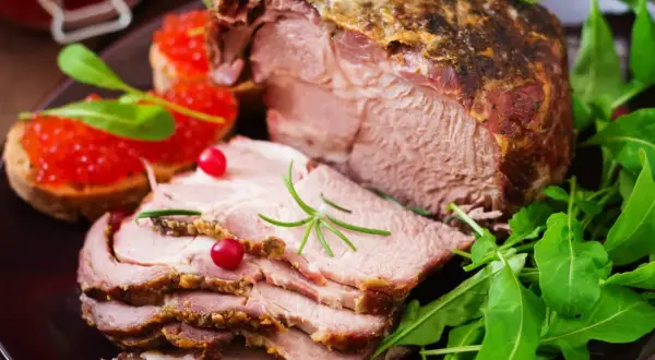 Pyszny, pieczony schab pokrojony w plastry, podany z kawiorową bruschettą i rukolą. Idealny na obiad, by dowiedzieć się, ile dusić schab do miękkości.