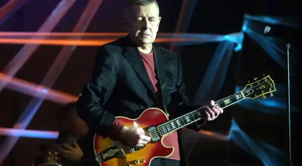Mężczyzna gra na gitarze, przypominając styl The Beatles "Let It Be (Remastered 2009)".