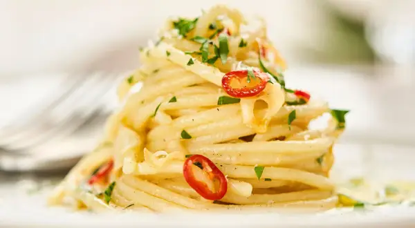 Ein Berg von Spaghetti Aglio e Olio, garniert mit frischer Petersilie und scharfen Chilischeiben.