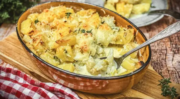 Herzhafter blumenkohl auflauf mit Kartoffeln und Käse überbacken, dampfend in einer Auflaufform.