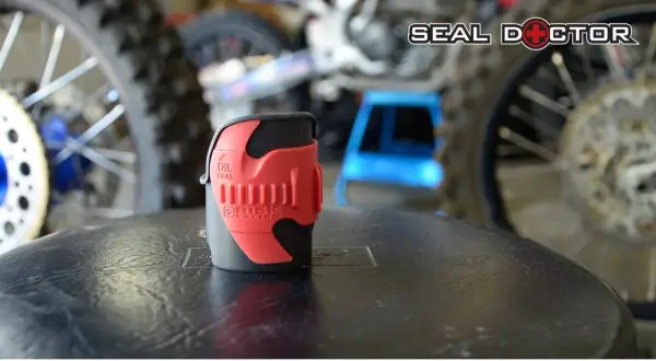 Herramienta roja para reparar horquilla moto, con logo "Seal Doctor" al fondo.