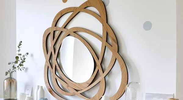 Miroir en bois au design entrelacé, parfait pour une diy deco murale. Des points colorés décorent le mur blanc.