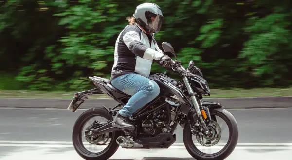 Motocyklista w kasku pędzi na czarnym Romet 125, pokonując kolejne 15 km.