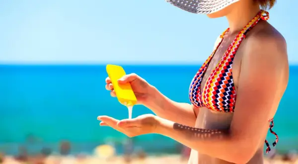 Frau trägt Sonnencreme auf, um sich vor der Sonne zu schützen. Wichtig: Sonnencreme mehrmals auftragen!
