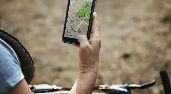 Rowerzysta sprawdza na telefonie mapę z trasą. Lokalizator GPS do roweru pomaga znaleźć drogę.