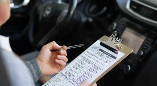 Persona revisa un formulario de solicitud de examen de manejo, preparándose para obtener su carnet coche automático.