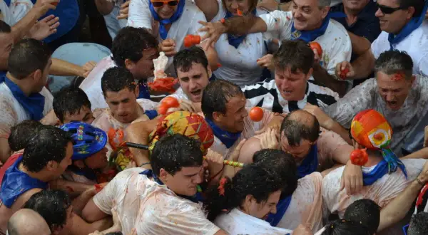 Multitud en fiestas de Tarazona, cubiertos de tomate, en medio de una batalla de tomates.