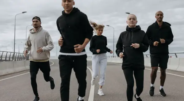 Grupa biegaczy w sportowych ubraniach, idealnych na 10 stopni. Lekkie bluzy i spodnie zapewniają komfort podczas treningu.