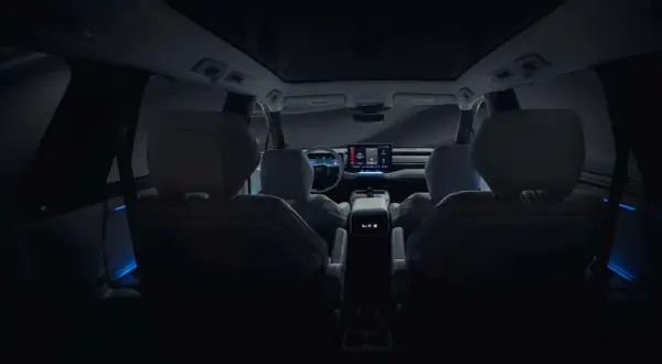 Wnętrze nowego Toyota Highlander nocą, z niebieskim nastrojowym oświetleniem i dużym ekranem multimedialnym.