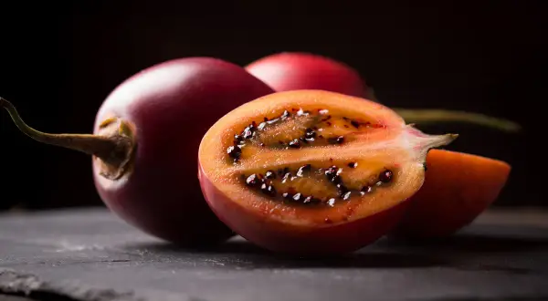 Tamarillo jak jeść? Pokrojone na pół, z widocznym miąższem i czarnymi nasionami, zachęca do spróbowania.