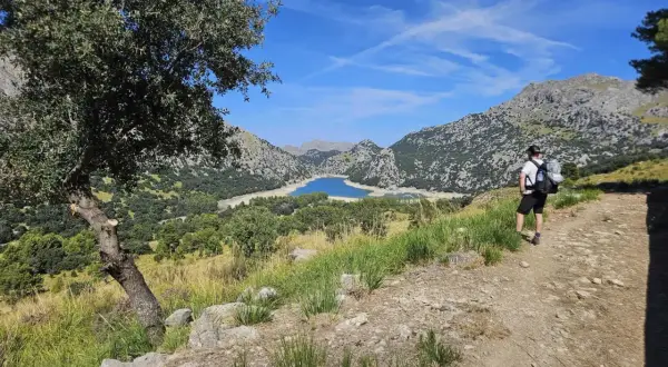 Randonneur contemplant le lac du Gorg Blau, un paysage emblématique du GR221 à Majorque.